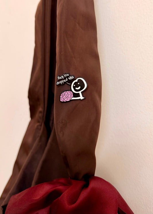 Currently Loading Enamel Pin, smiling character handing over a pink brain