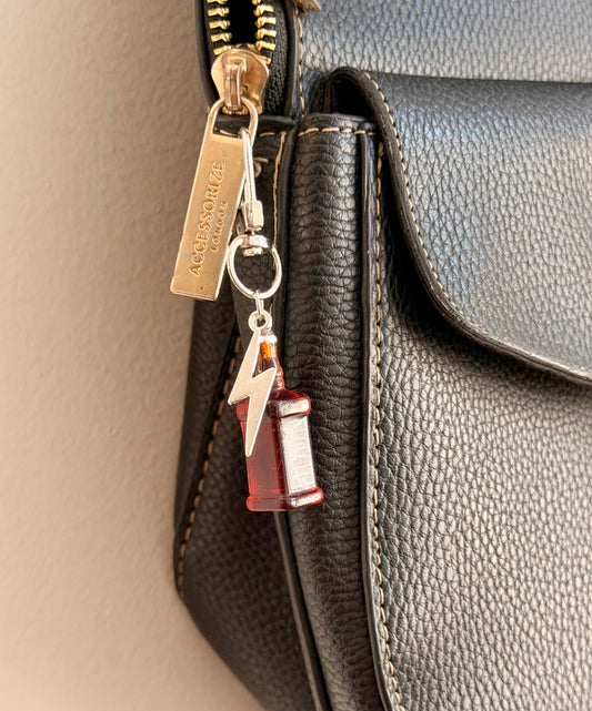 Jack daniels with Thunderbolt, a miniature whiskey bottle with a silver thunderbolt charm clipped to a black leather handbag zip.