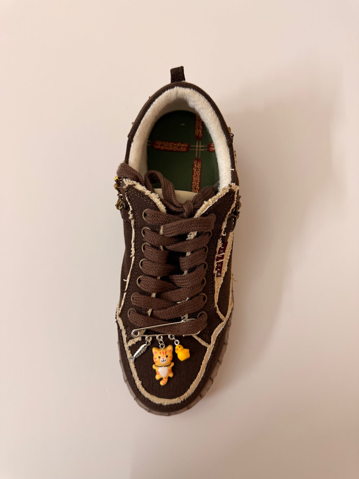 Orange Cat Charm, brooch pin fastened to the laces of a brown canvas sneaker