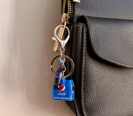 Pepsi Break, a blue cola crate with a glass bottle clipped to a black leather handbag zip.