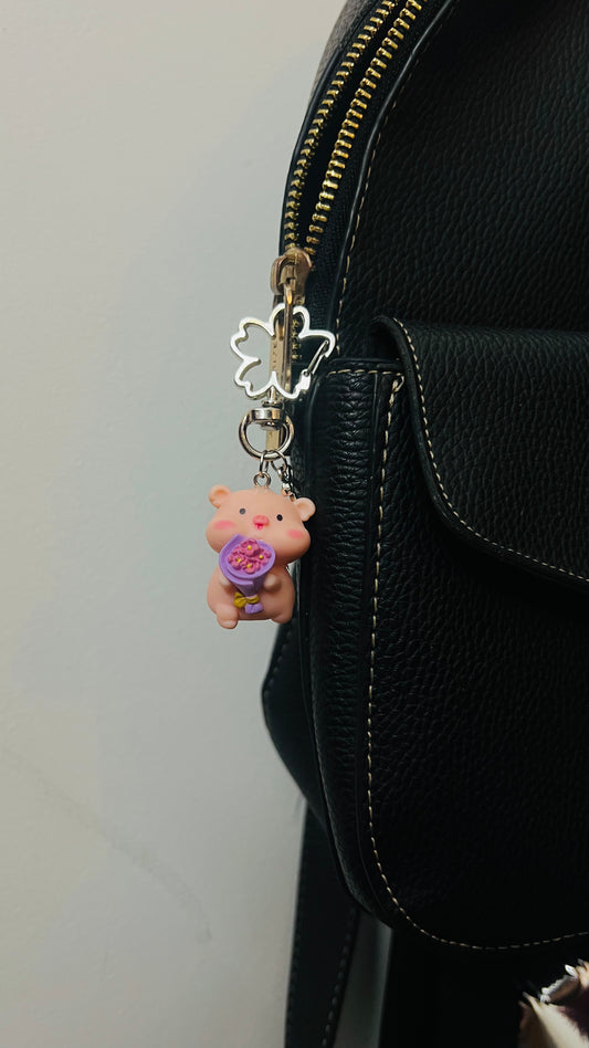 Pink Piggu piglet bag charm holding a purple bouquet of flowers (view 2)