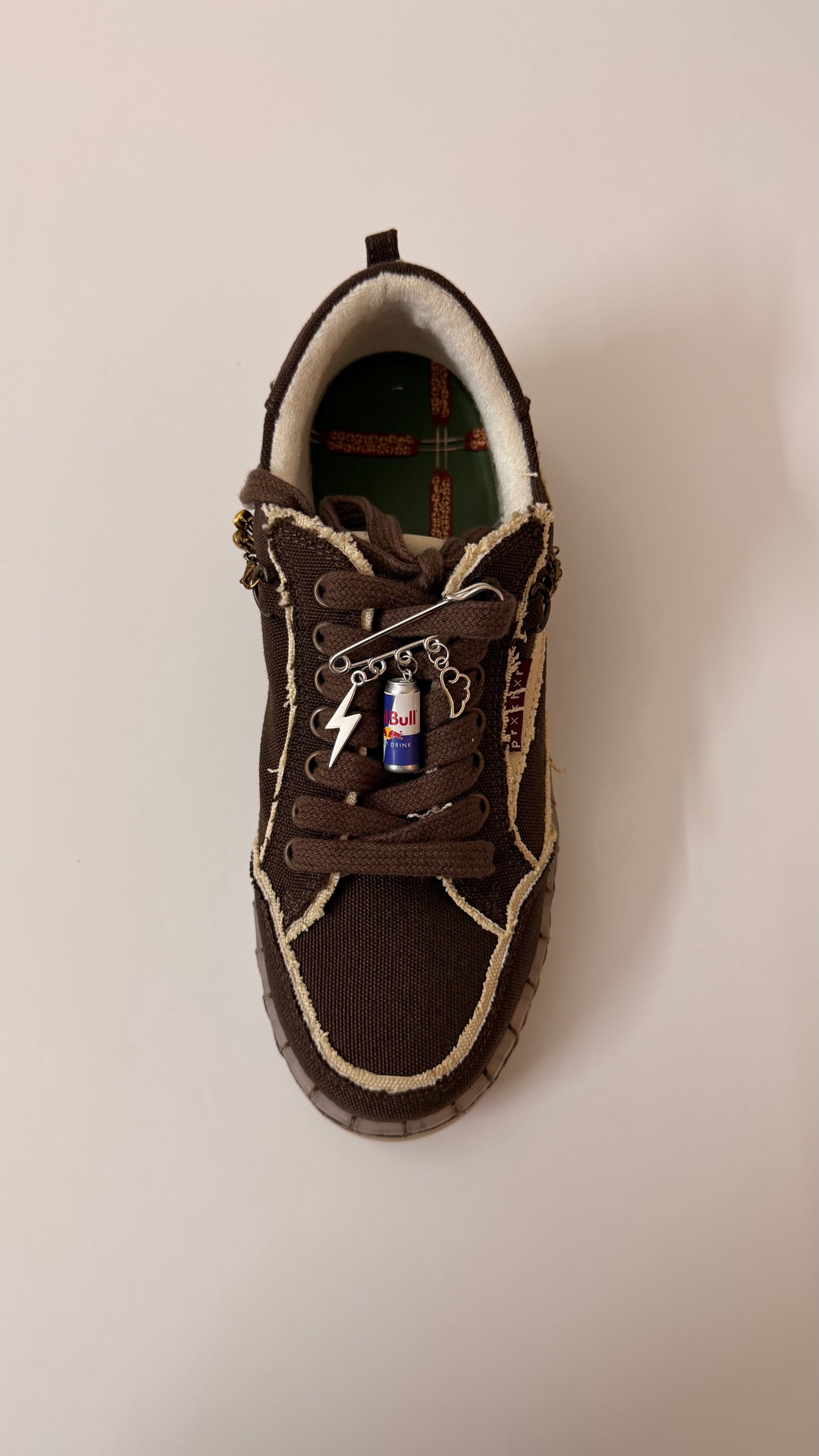 Red Bull Gives You Wings, brooch pin fastened to the laces of a brown canvas sneaker