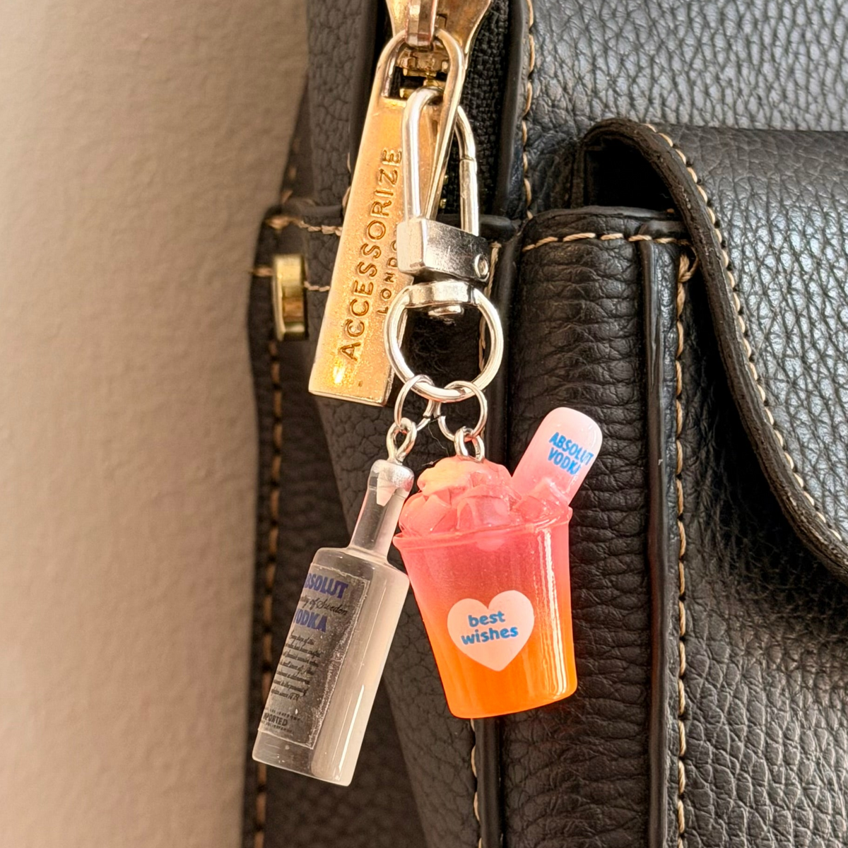 Absolut Orange Cocktail Bag Charm, a miniature clear Absolut vodka bottle with an orange cocktail cup.