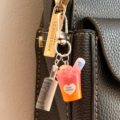 Absolut Orange Cocktail Bag Charm, a miniature clear Absolut vodka bottle with an orange cocktail cup.