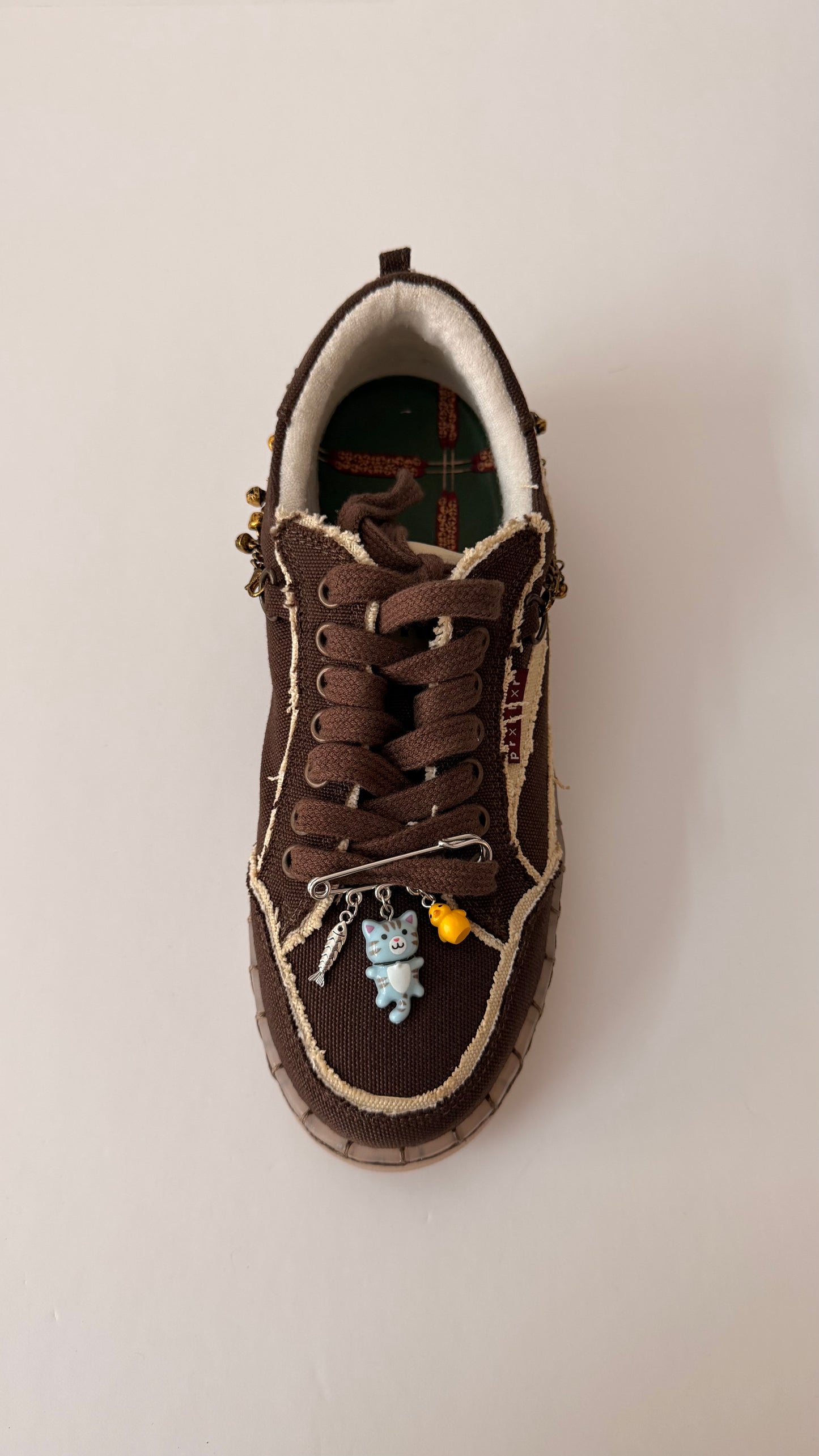 Blue Cat Charm, brooch pin fastened to the laces of a brown canvas sneaker