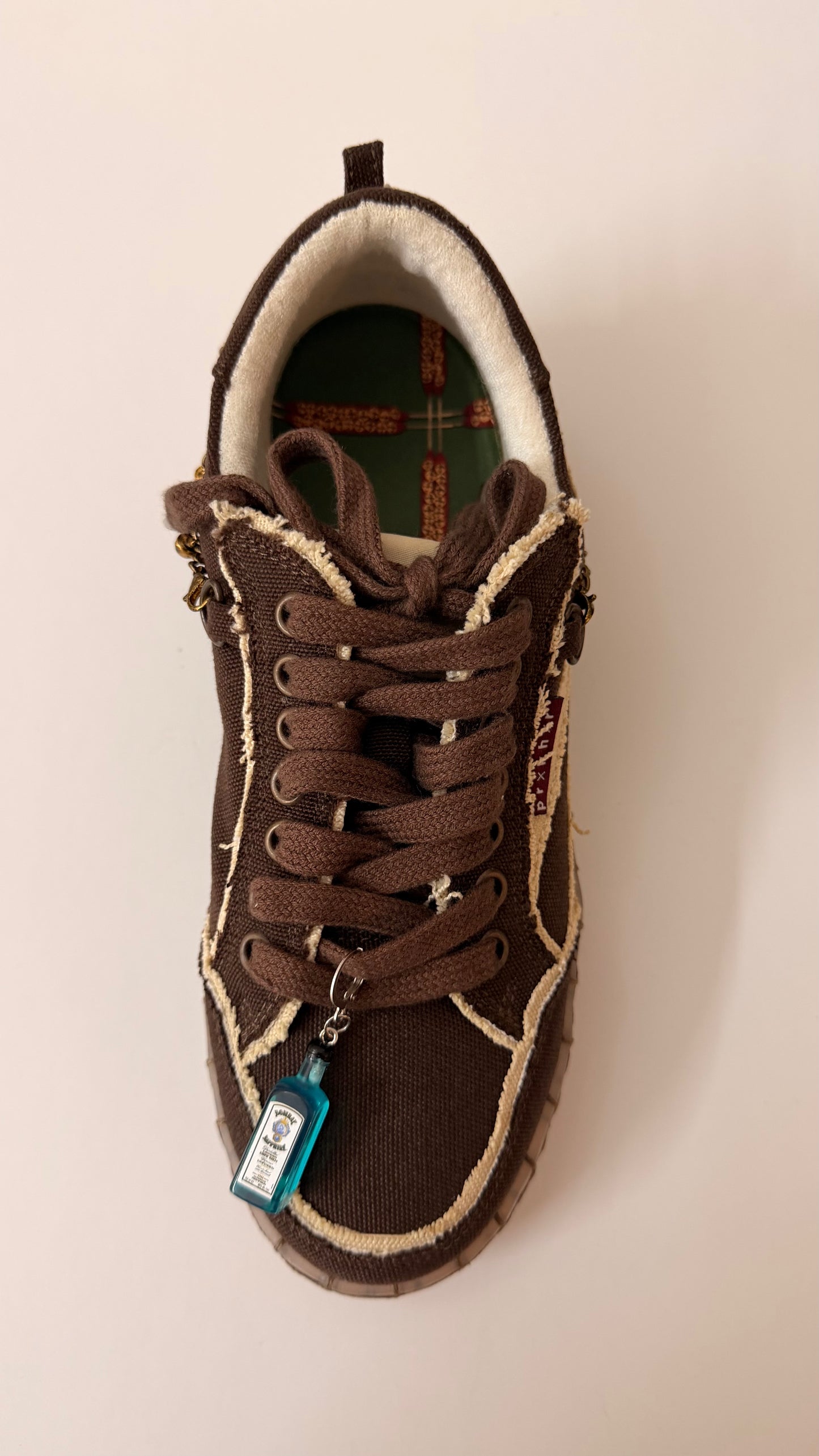 Bombay Sapphire Shoe Charm, mini blue Bombay Sapphire gin bottle charm on the laces of a brown canvas sneaker, full shoe view