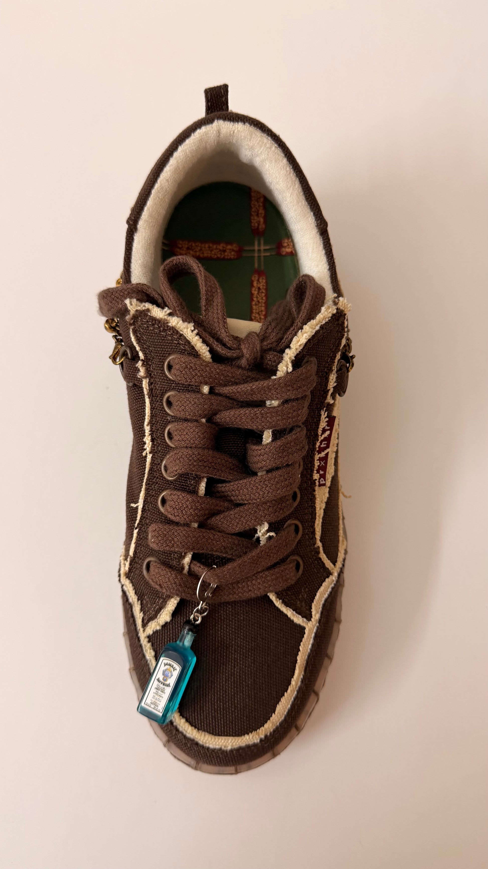 Bombay Sapphire Shoe Charm, mini blue Bombay Sapphire gin bottle charm on the laces of a brown canvas sneaker, full shoe view