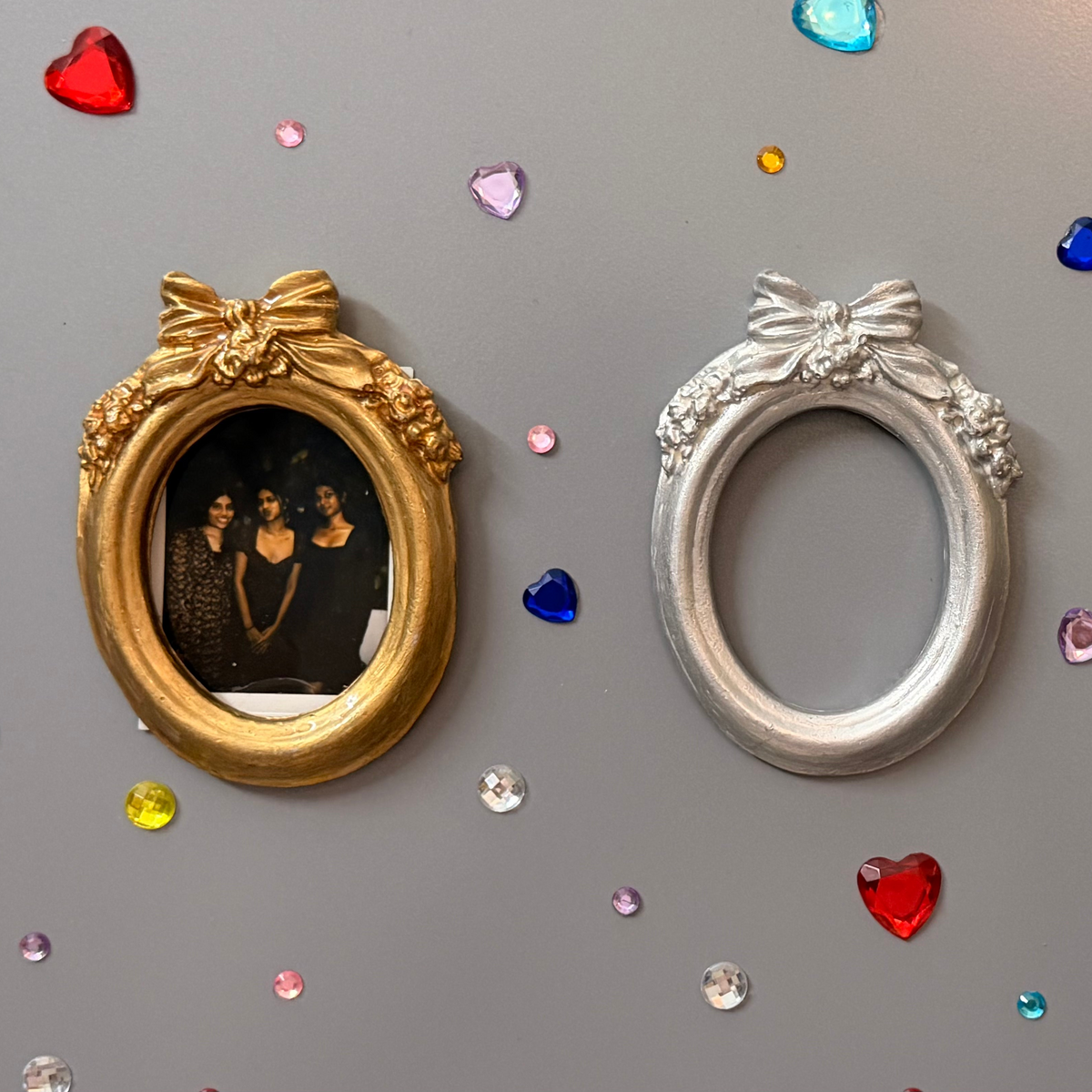 Bow and Blooms Magnetic Frame, three concrete oval frames on a fridge door, gold holding a photo, silver empty and gold empty