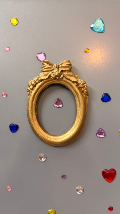 Bow and Blooms Magnetic Frame, empty gold concrete oval frame showing the sculpted bow and blooms detail