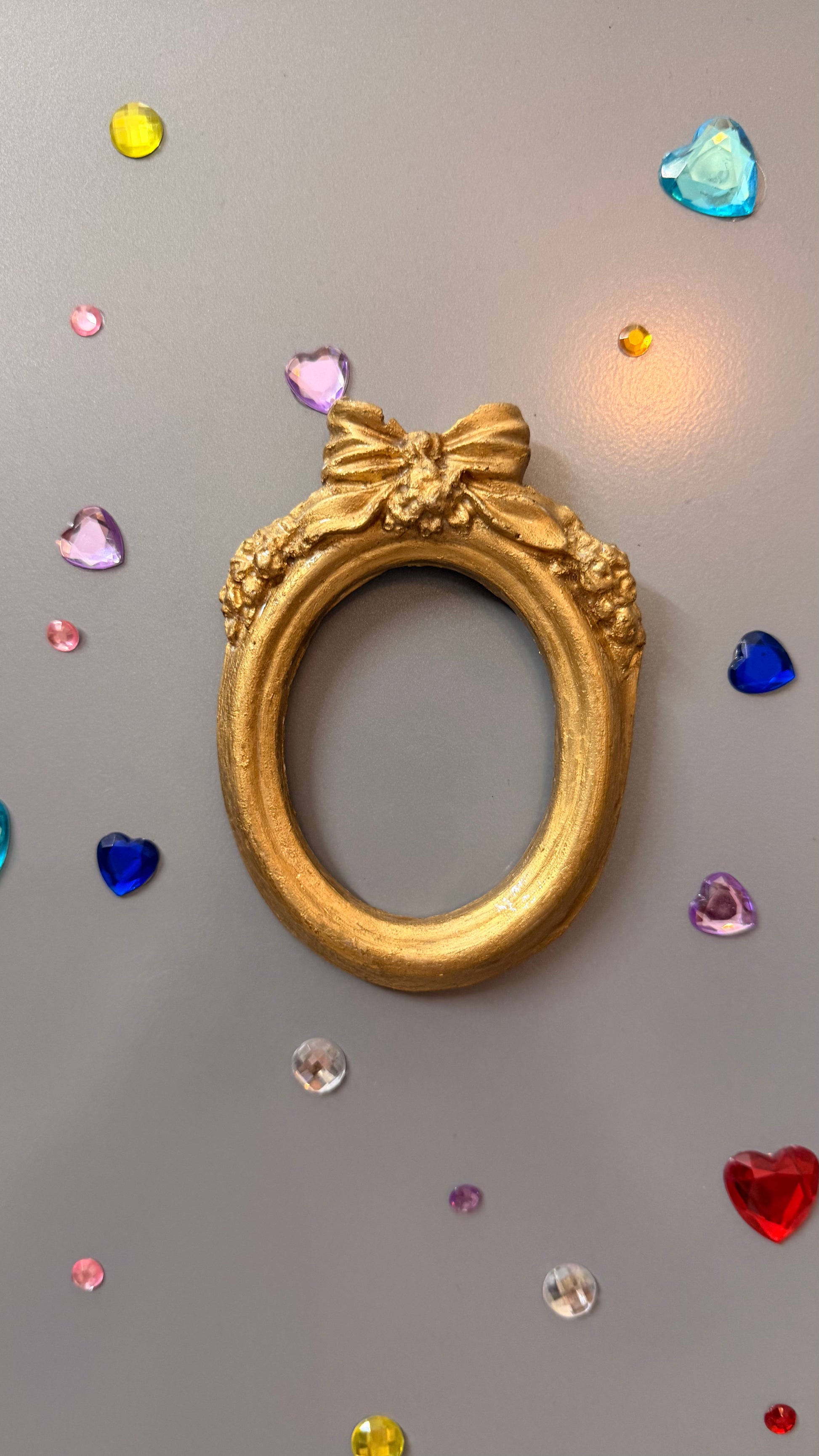 Bow and Blooms Magnetic Frame, close view of the gold concrete oval frame and its sculpted ribbon bow