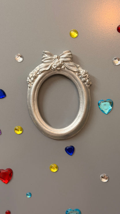 Bow and Blooms Magnetic Frame, silver concrete oval frame with a sculpted bow and floral garlands