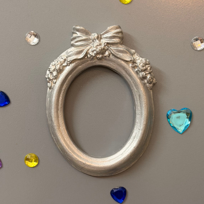 Bow and Blooms Magnetic Frame, silver concrete oval frame with a sculpted bow and floral garlands