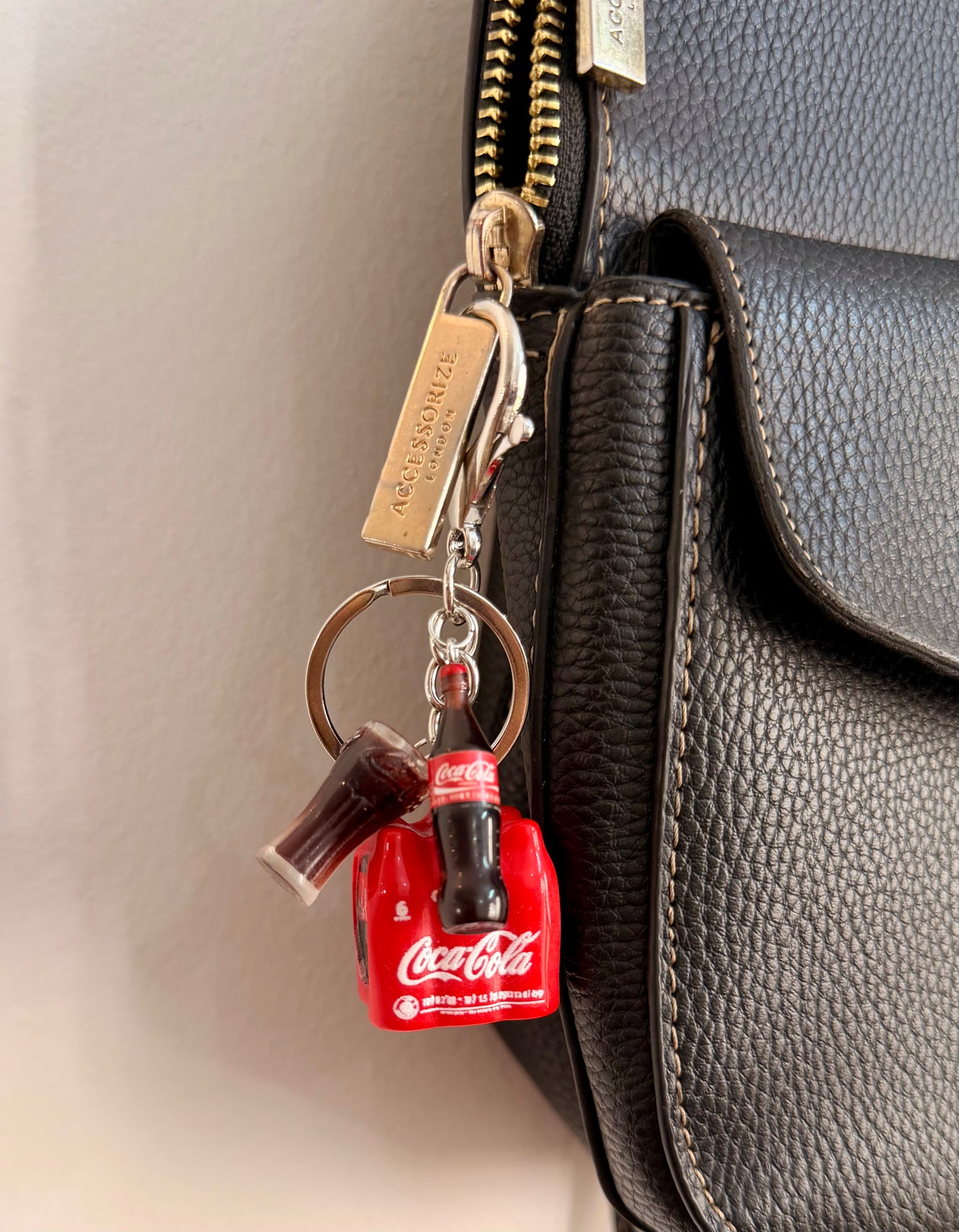 Coke Break, a red cola crate with a glass bottle and a tall glass clipped to a black leather handbag zip.