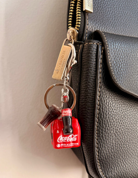 Coke Break, a red cola crate with a glass bottle and a tall glass clipped to a black leather handbag zip.