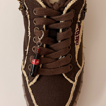 Coke Bottle Shoe Charm, mini Coca-Cola glass bottle charm on the laces of a brown canvas sneaker