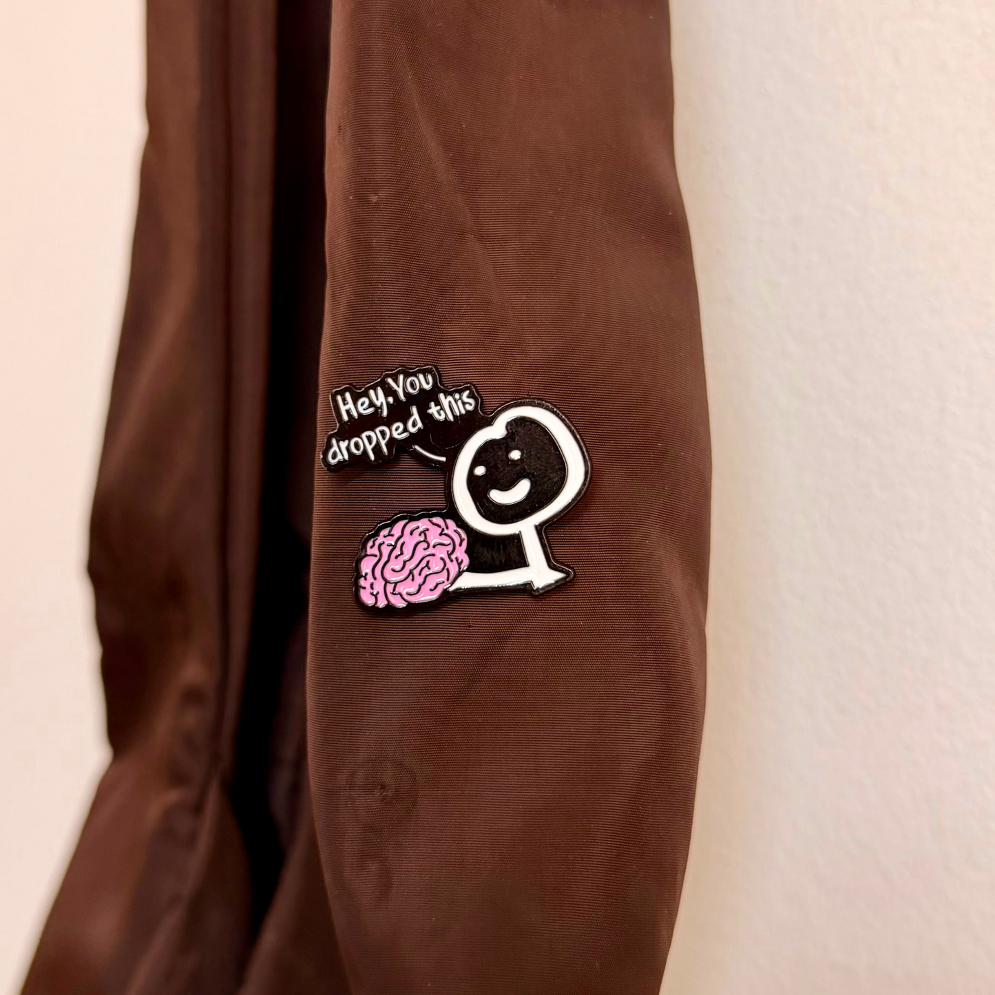 Currently Loading Enamel Pin, smiling character handing over a pink brain