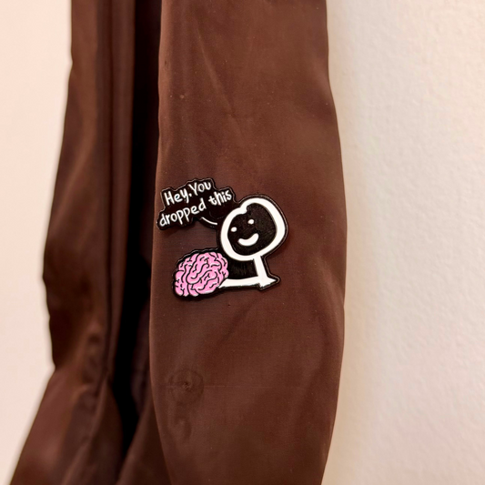 Currently Loading Enamel Pin, smiling character handing over a pink brain