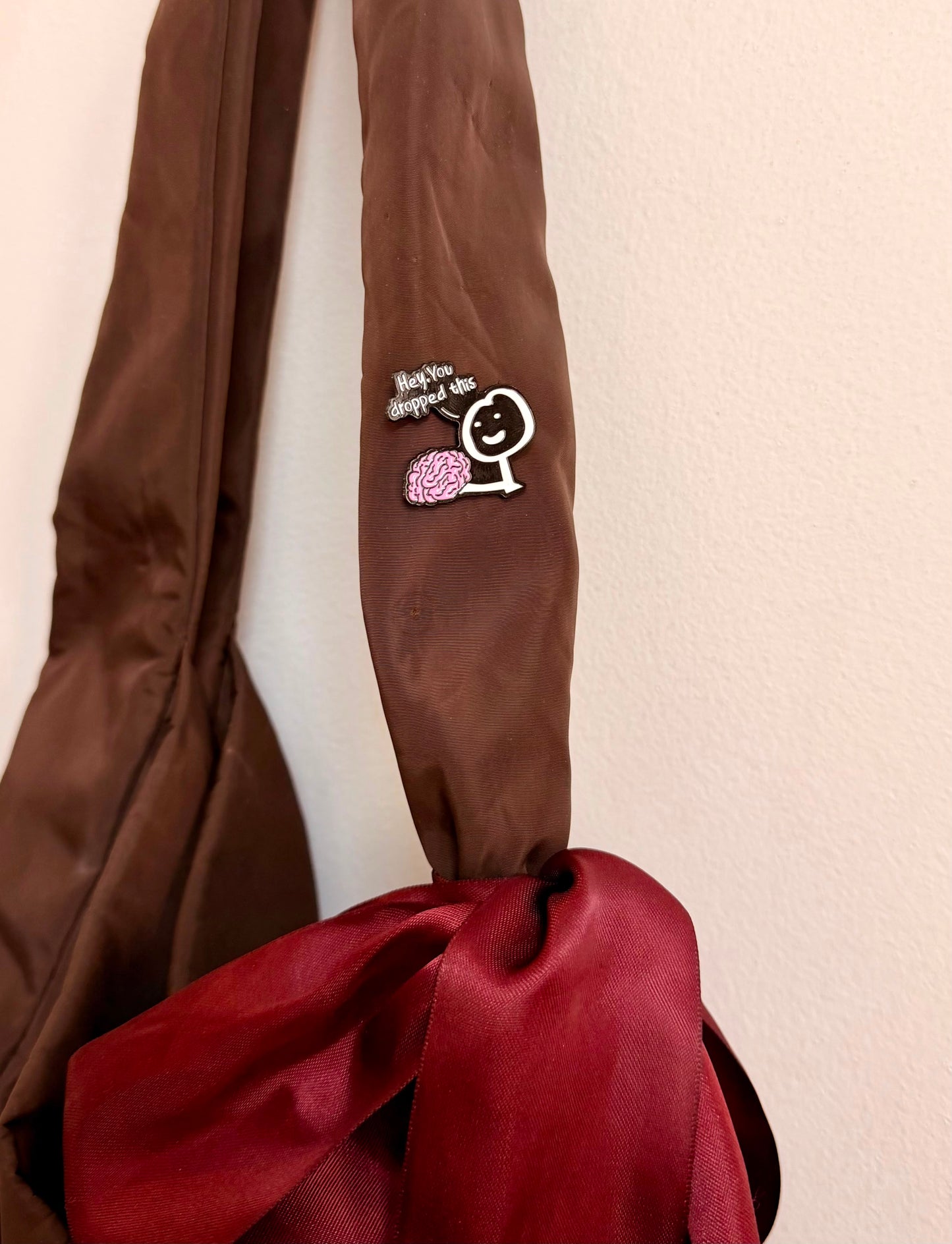 Currently Loading Enamel Pin, smiling character handing over a pink brain