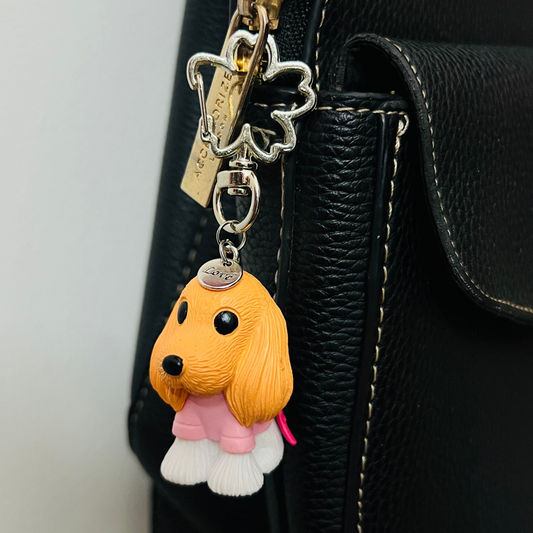 Golden puppy bag charm dressed in a pink outfit