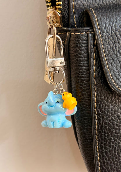 Ducky and Dumbo, a blue baby elephant with a yellow duckling on its trunk shown from another angle.