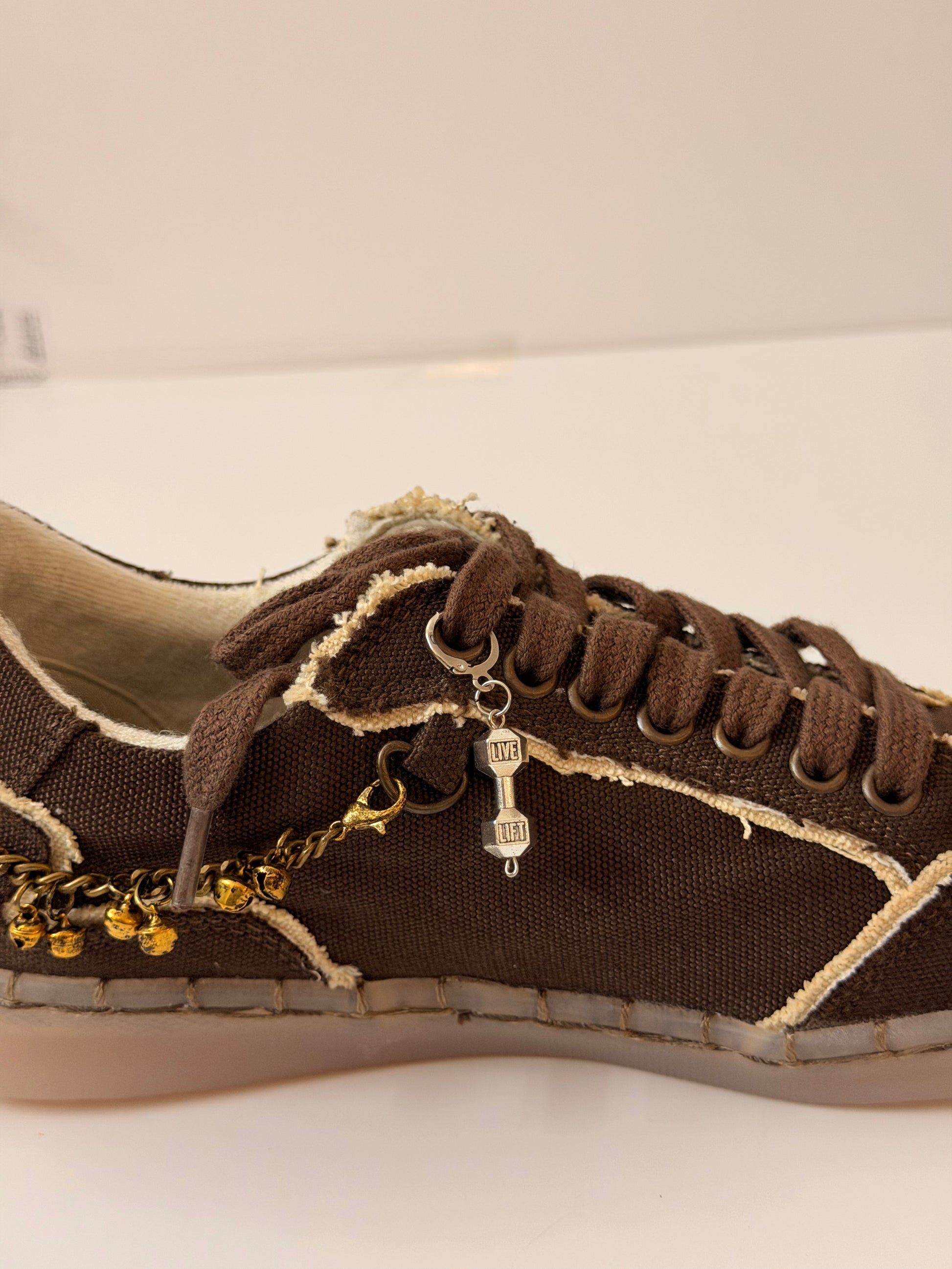 Dumbbell Shoe Charm, silver LIVE LIFT dumbbell charm on the laces of a brown canvas sneaker