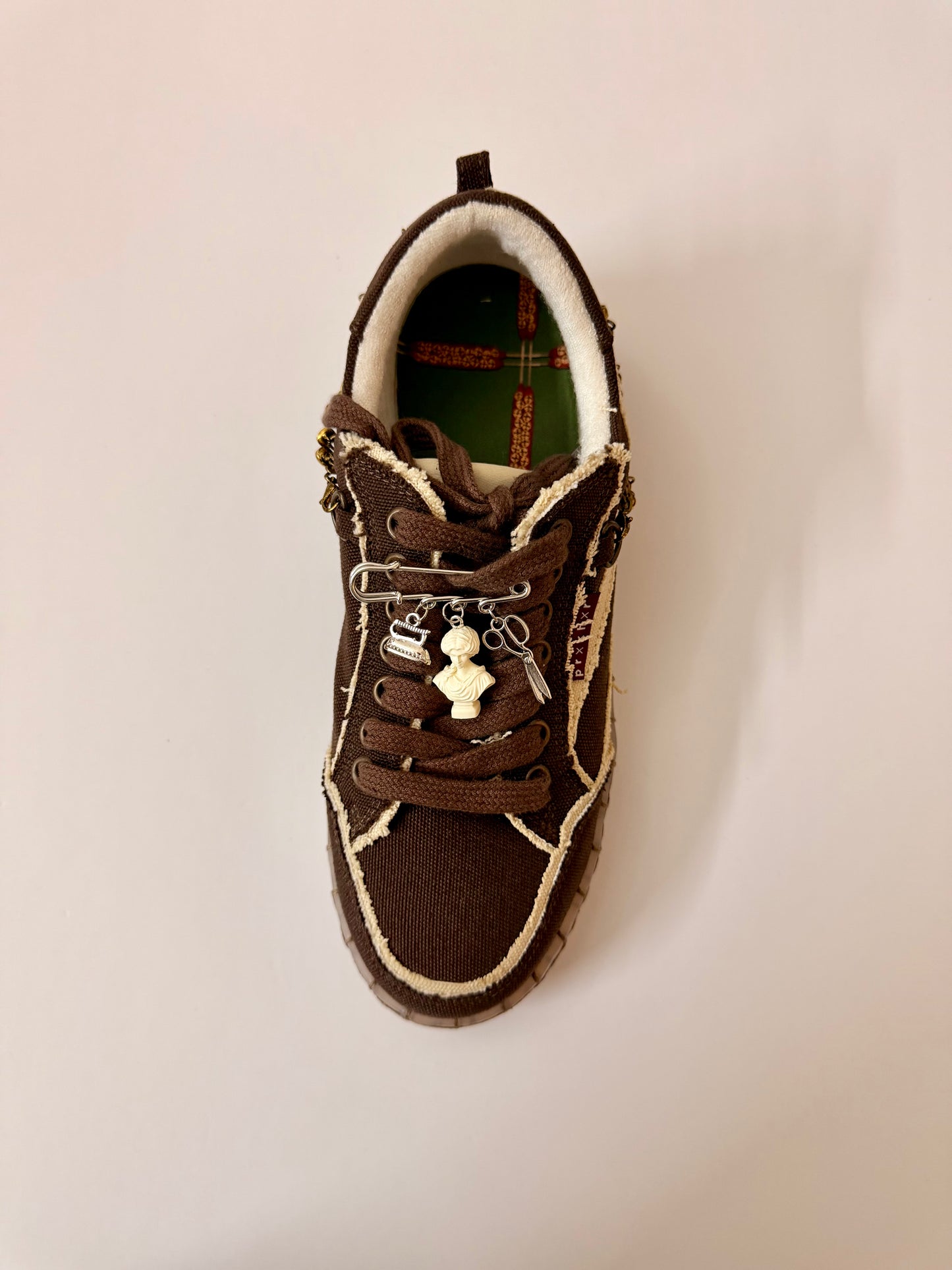 Fashionably Late, brooch pin fastened to the laces of a brown canvas sneaker