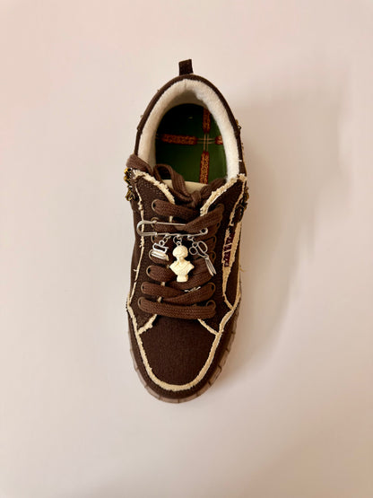 Fashionably Late, brooch pin fastened to the laces of a brown canvas sneaker