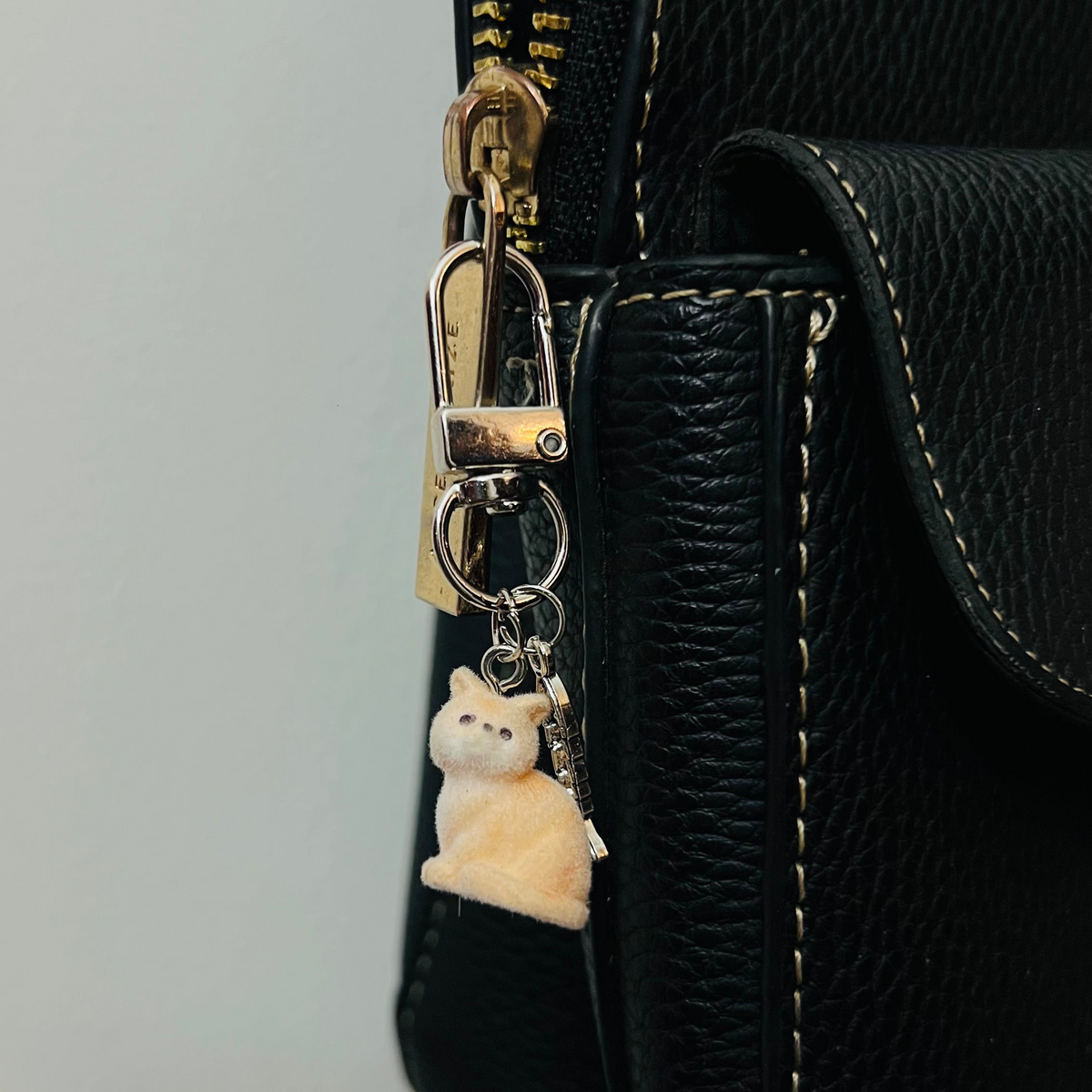 Furry orange cat bag charm with a silver fish charm