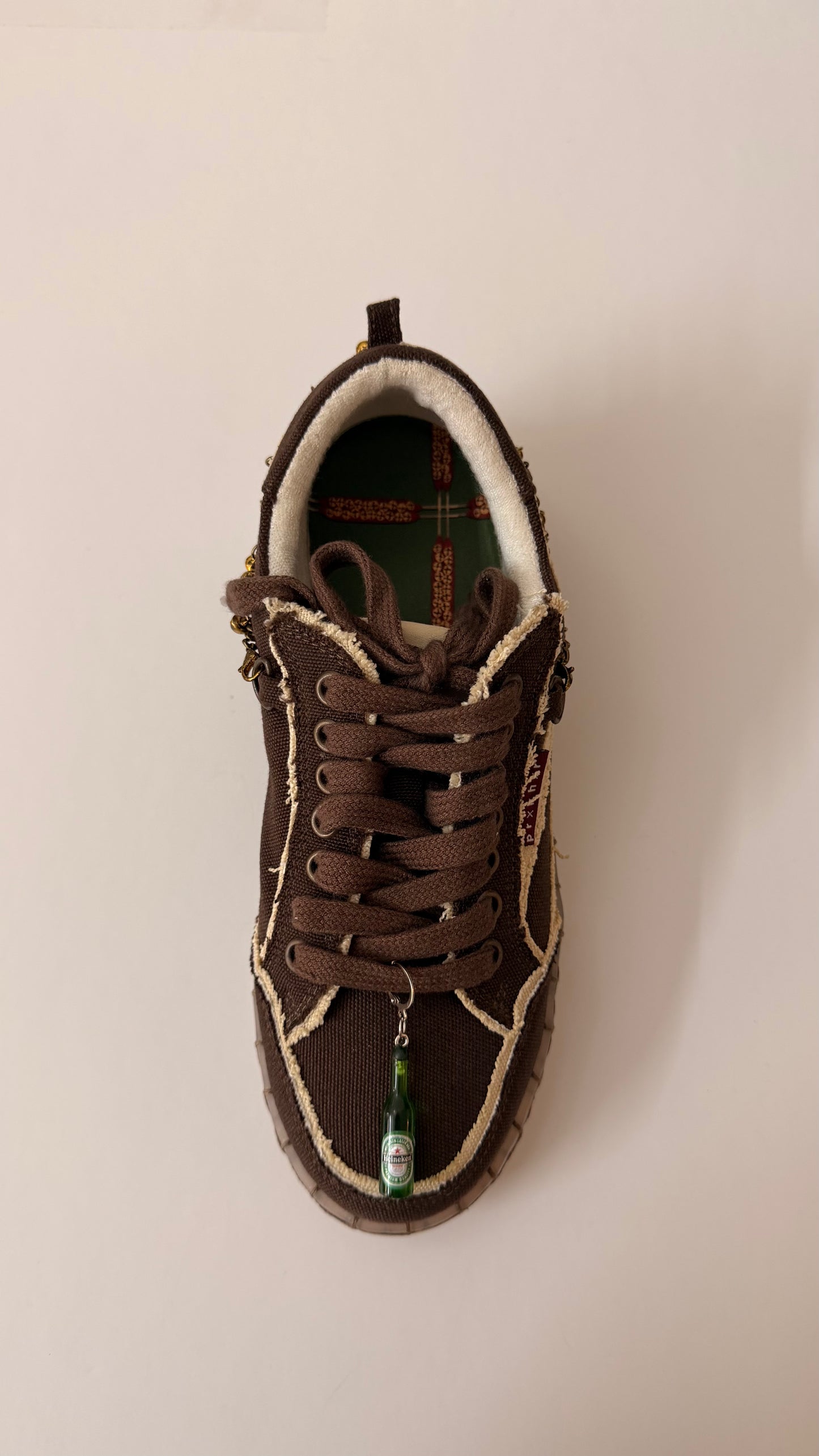 Heineken Shoe Charm, mini green Heineken beer bottle charm on the laces of a brown canvas sneaker