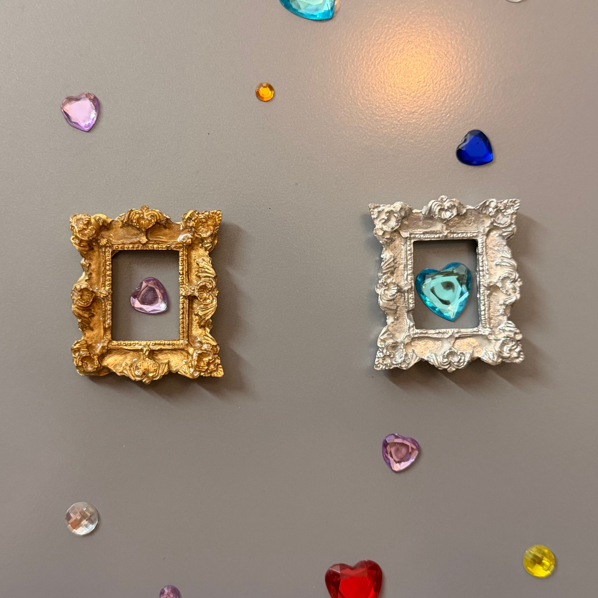 The Relic Magnetic Frame, gold and silver concrete miniature rococo frames side by side on a fridge door
