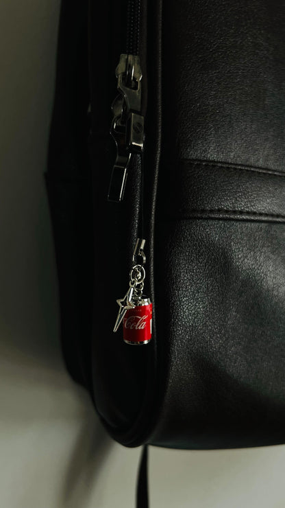 Red Coca-Cola can charm with silver star pendant on a black bag zipper