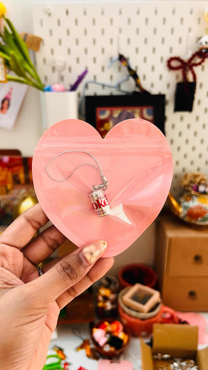 Metallic Diet Coke can phone charm with silver strap in a pink heart-shaped gift pouch held in hand