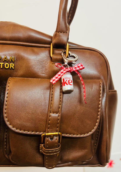 White Diet Coke can charm with red gingham bow and heart clasp on a brown leather handbag