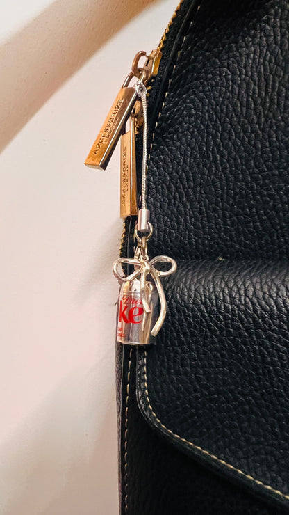 Metallic Diet Coke can charm with silver bow on a silver strap, on a black pebbled handbag