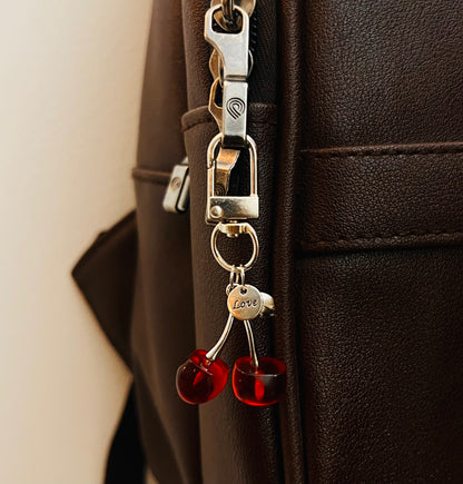 Red cherry charm with silver Love heart tag hanging from a bag clasp