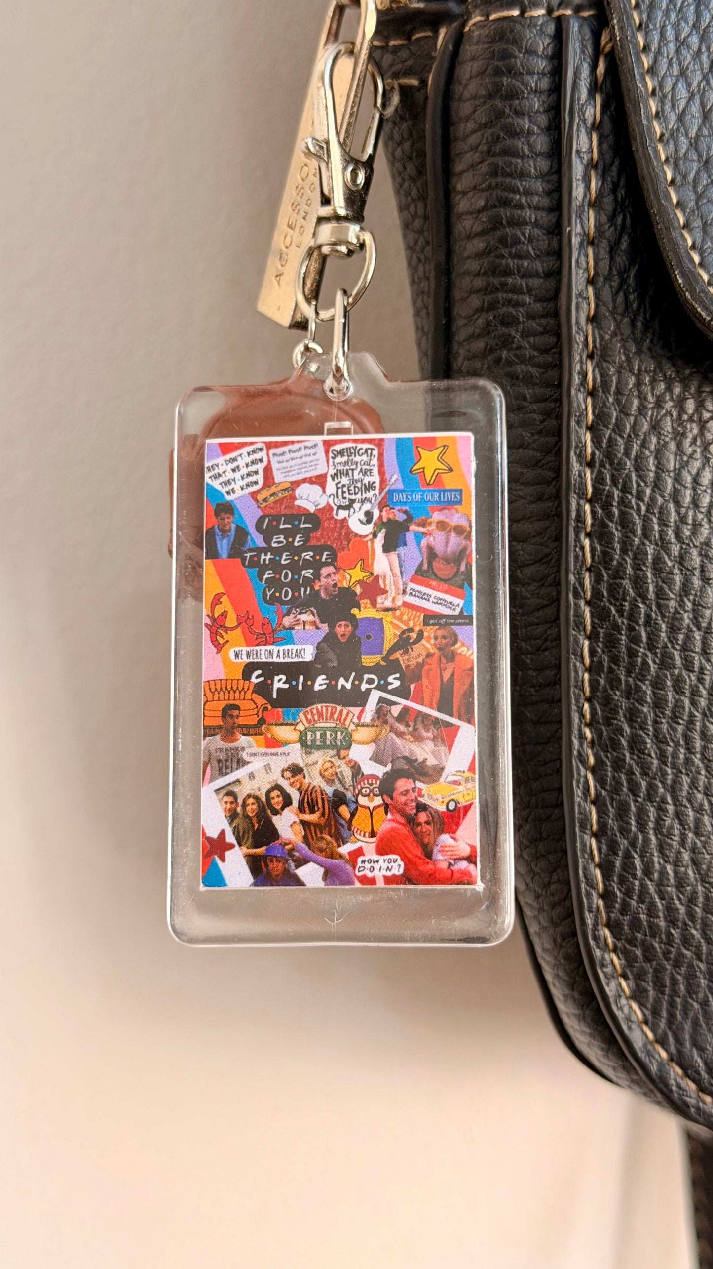 I'll be there for you.., a clear acrylic sitcom collage card with a brown armchair charm clipped to a black leather handbag zip.