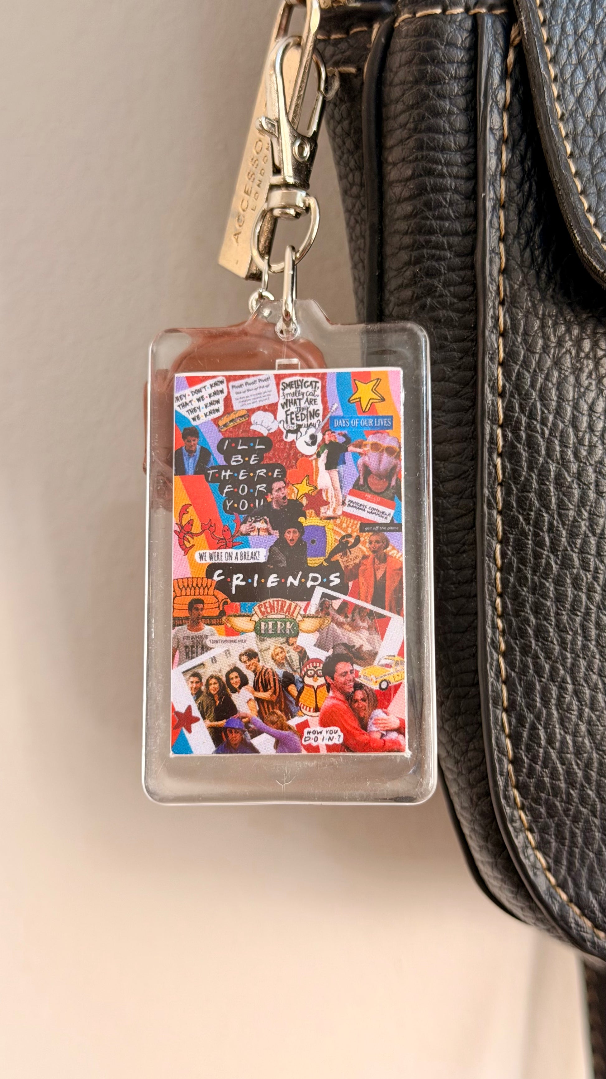I'll be there for you.., a clear acrylic sitcom collage card with a brown armchair charm clipped to a black leather handbag zip.