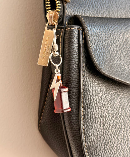 Jack daniels with Thunderbolt, a miniature whiskey bottle with a silver thunderbolt charm clipped to a black leather handbag zip.
