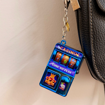 Jackpot, a blue casino slot machine charm with coin charms clipped to a black leather handbag zip.