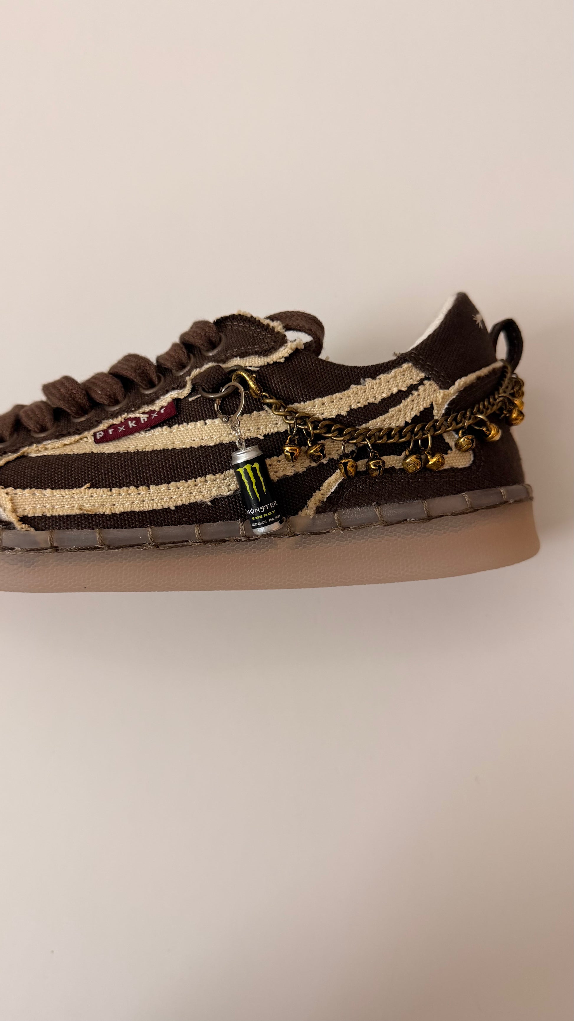 Black Monster Energy Shoe Charm, mini black Monster Energy can charm with the green claw logo on the laces of a brown canvas sneaker