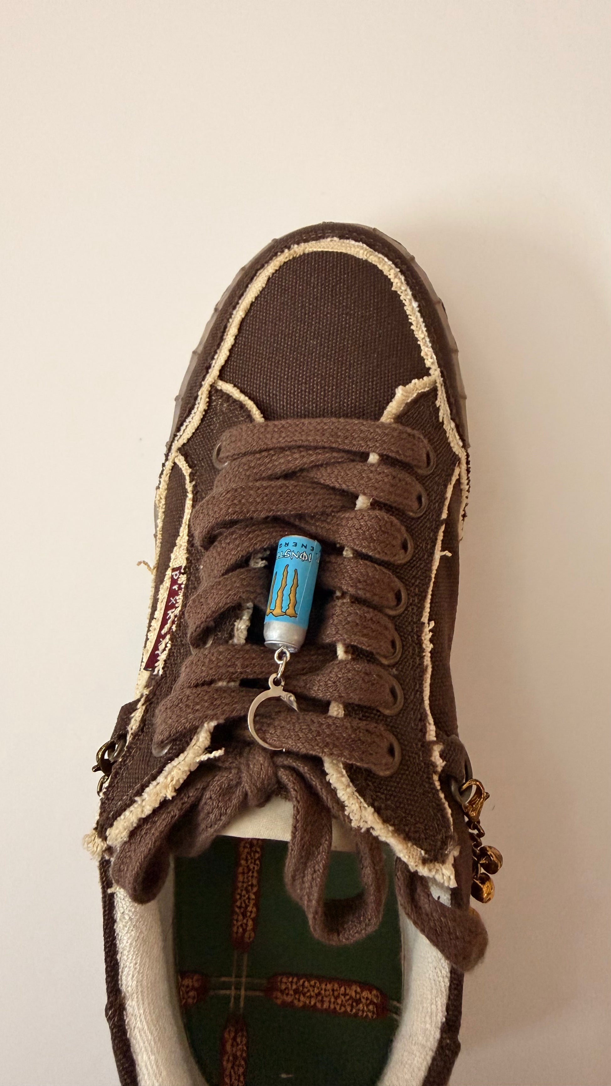 Blue Monster Energy Shoe Charm, mini light blue Monster Energy can charm on the laces of a brown canvas sneaker, from the heel