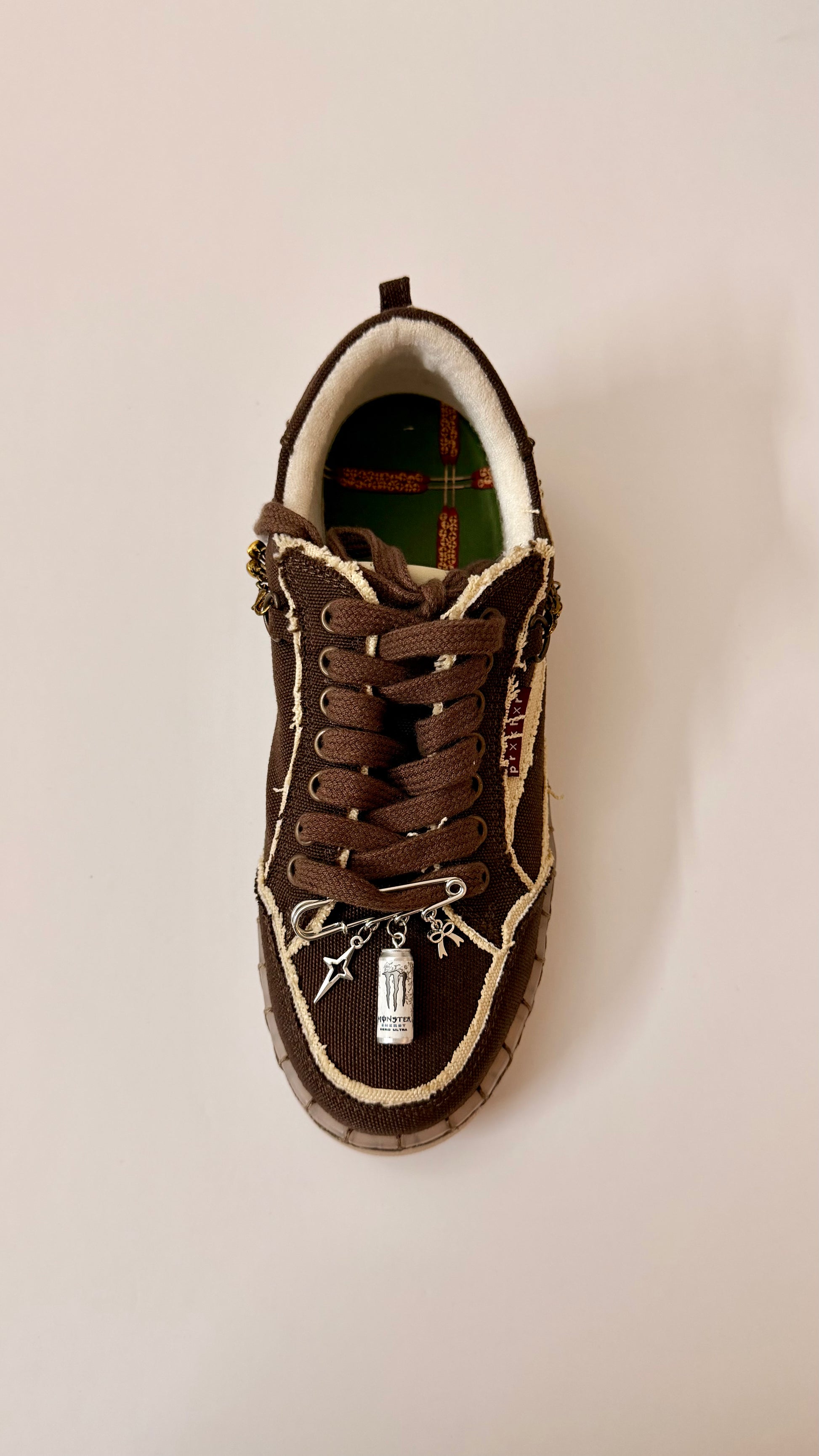 No Sleep Club, brooch pin fastened to the laces of a brown canvas sneaker