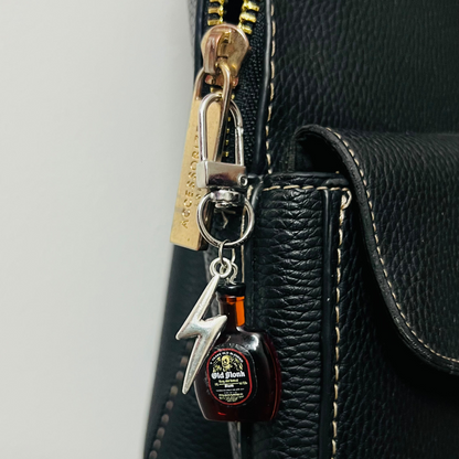 Old Monk rum bottle bag charm with a silver thunderbolt charm