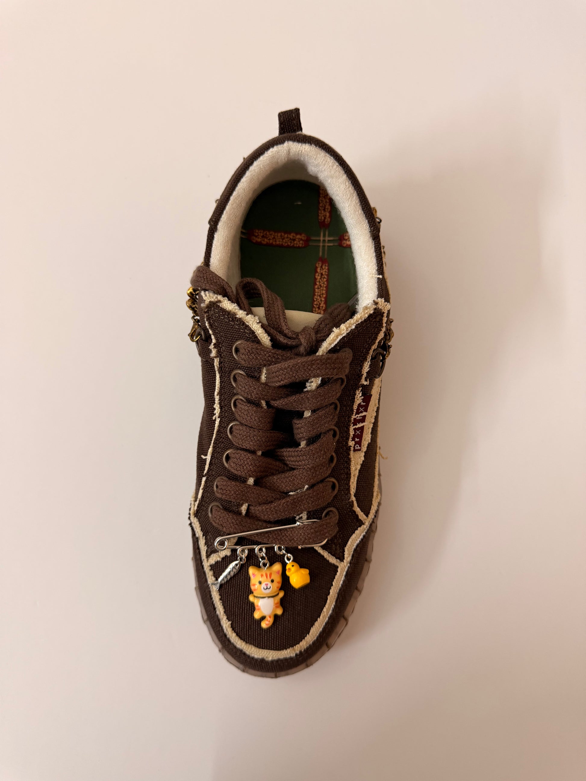 Orange Cat Charm, brooch pin fastened to the laces of a brown canvas sneaker