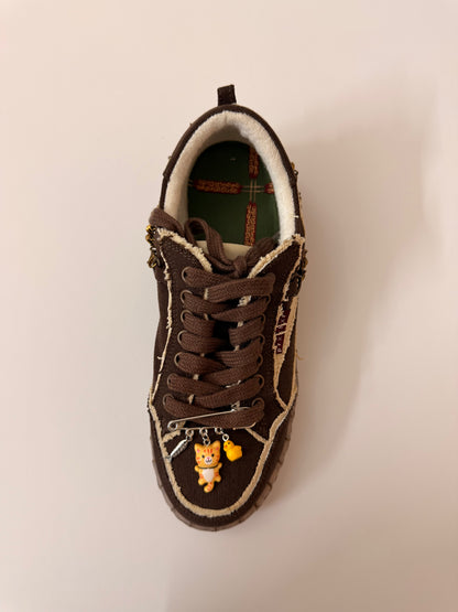 Orange Cat Charm, brooch pin fastened to the laces of a brown canvas sneaker