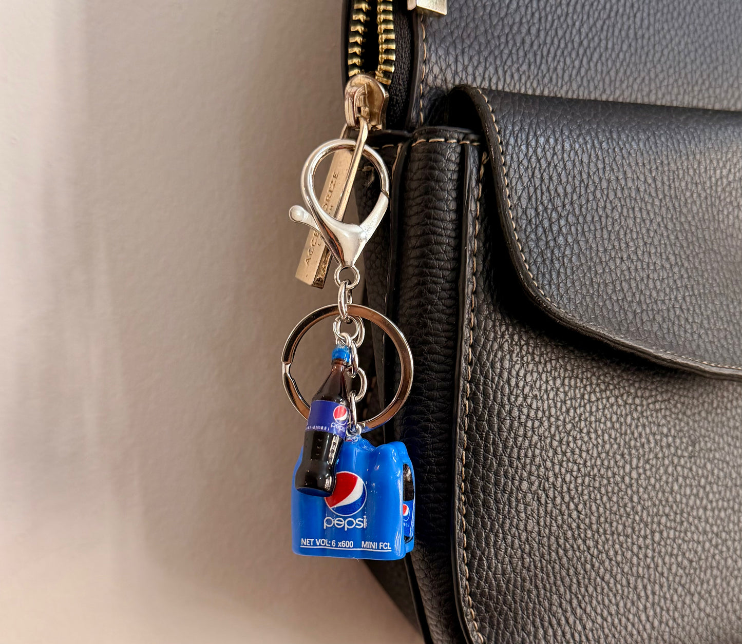 Pepsi Break, a blue cola crate with a glass bottle clipped to a black leather handbag zip.