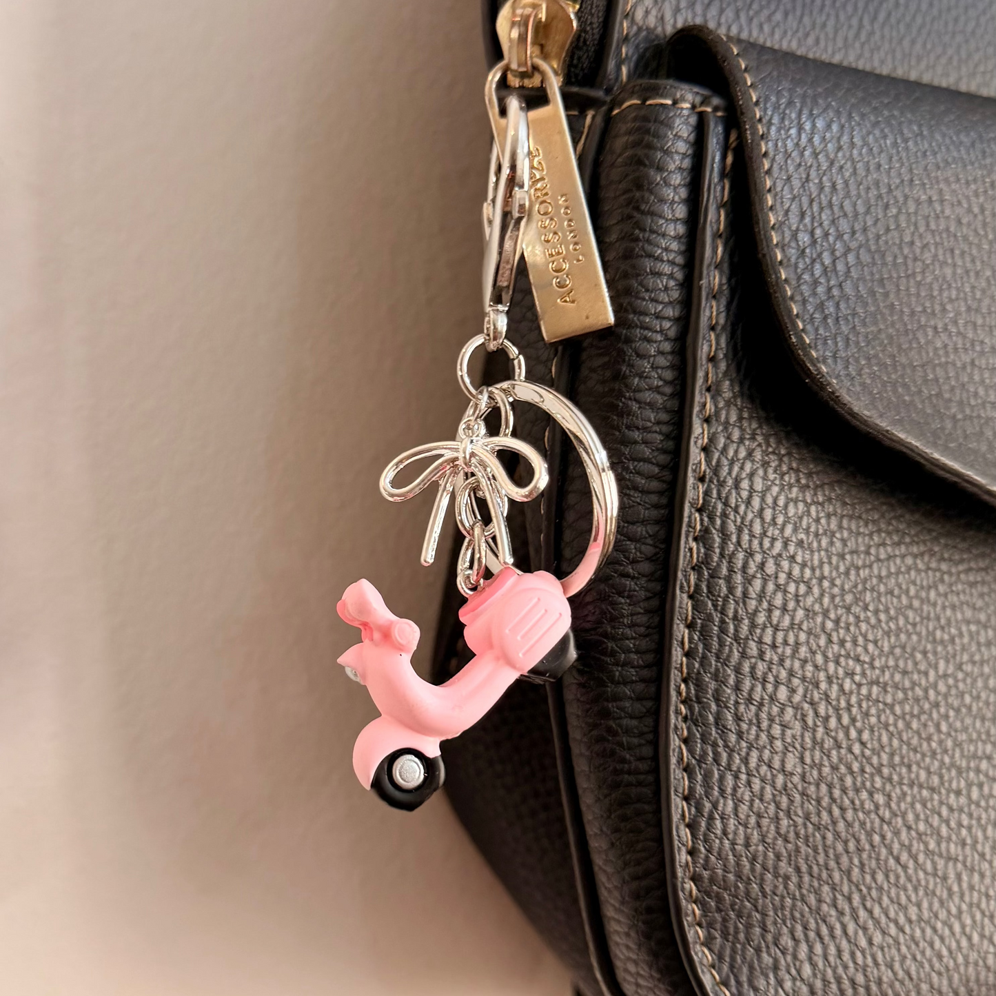 Pink Vespa bag charm, a pink scooter with a silver ribbon bow.
