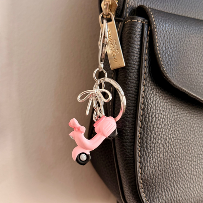 Pink Vespa bag charm, a pink scooter with a silver ribbon bow.