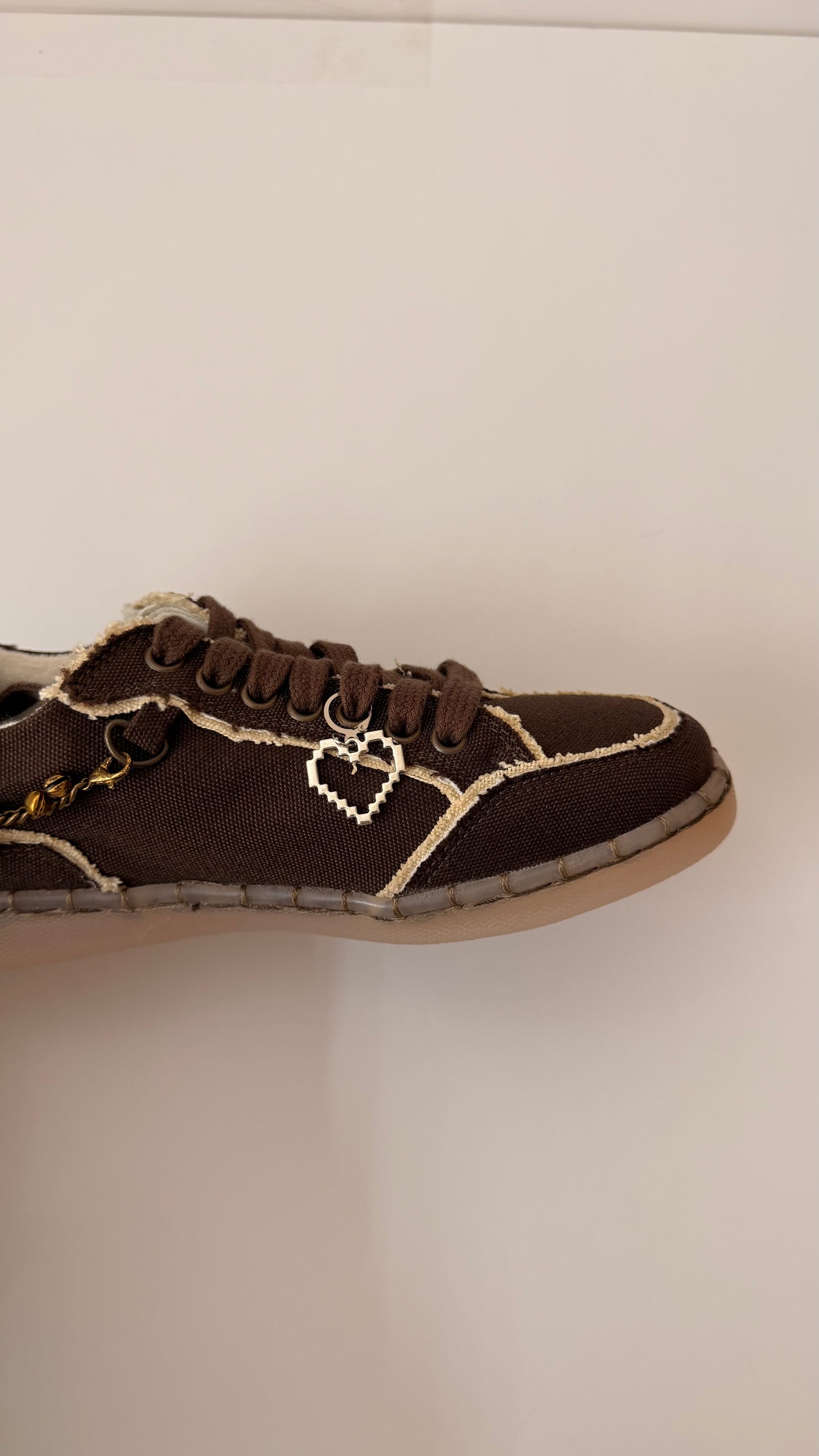Pixel Heart Shoe Charm, open silver pixel heart charm on the laces of a brown canvas sneaker