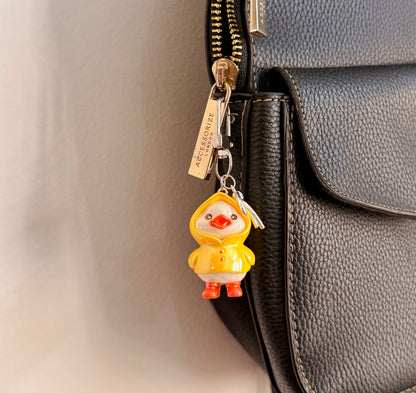 Rainy Day Duck, a yellow duck in a raincoat with the hood up and orange boots clipped to a black leather handbag zip.